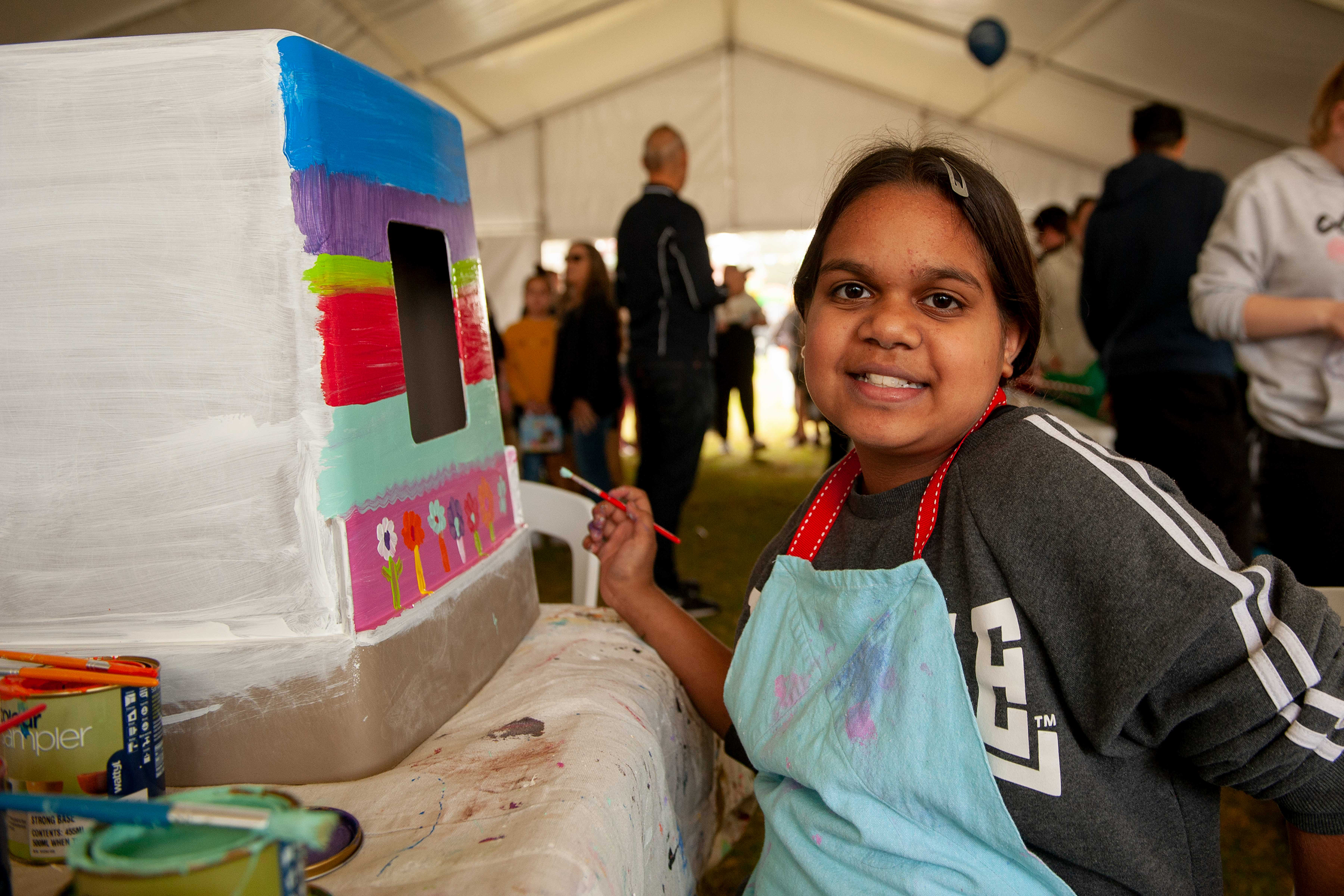 A happy child painting on a large white box