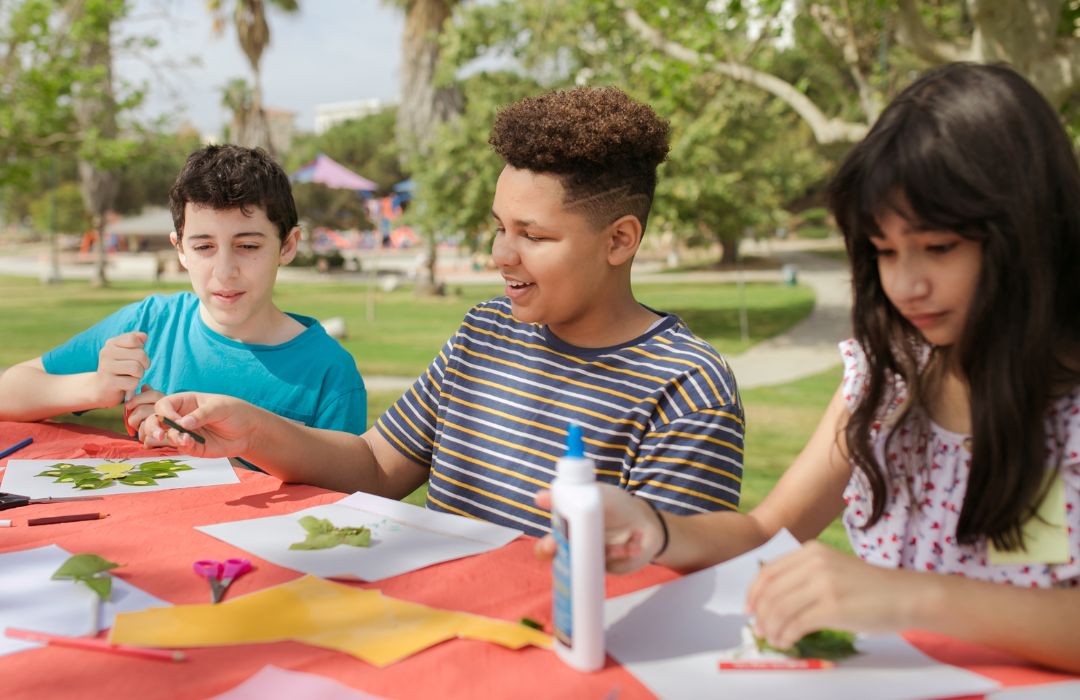 A group of kids creating nature craft outdoors