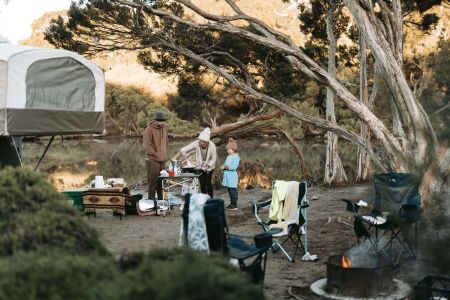 Photo of a family in a calm campsite by a river