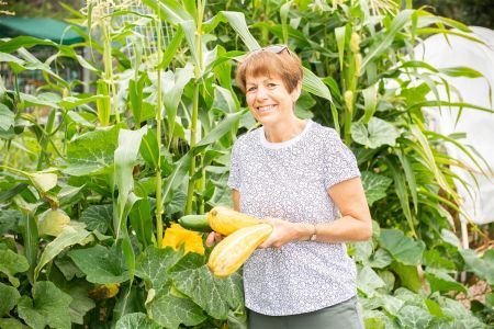 Lady holding some vegetables in a community garden.