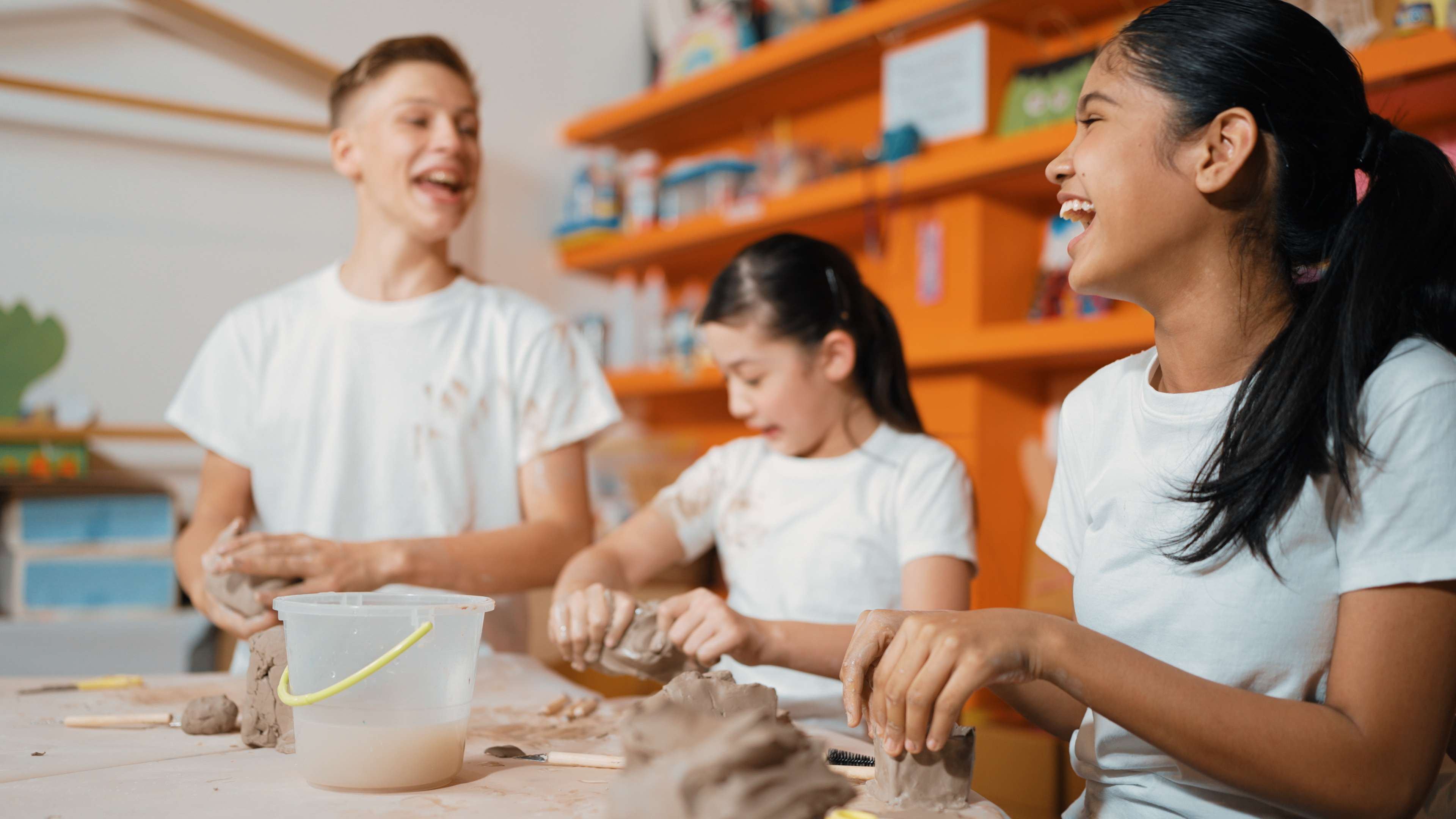 Three children working at a bench with clay