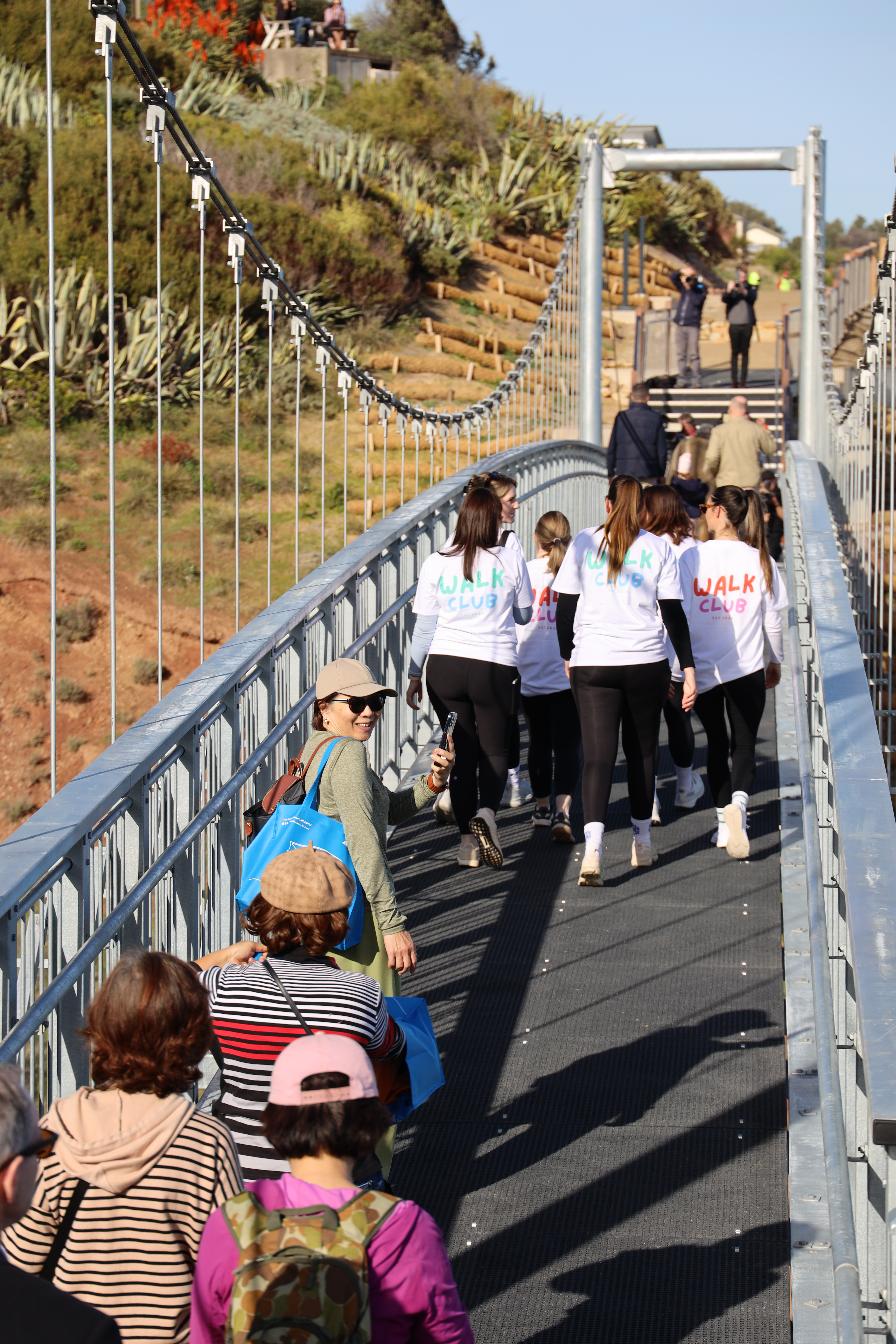 A group of children and walking club walk across the bridge