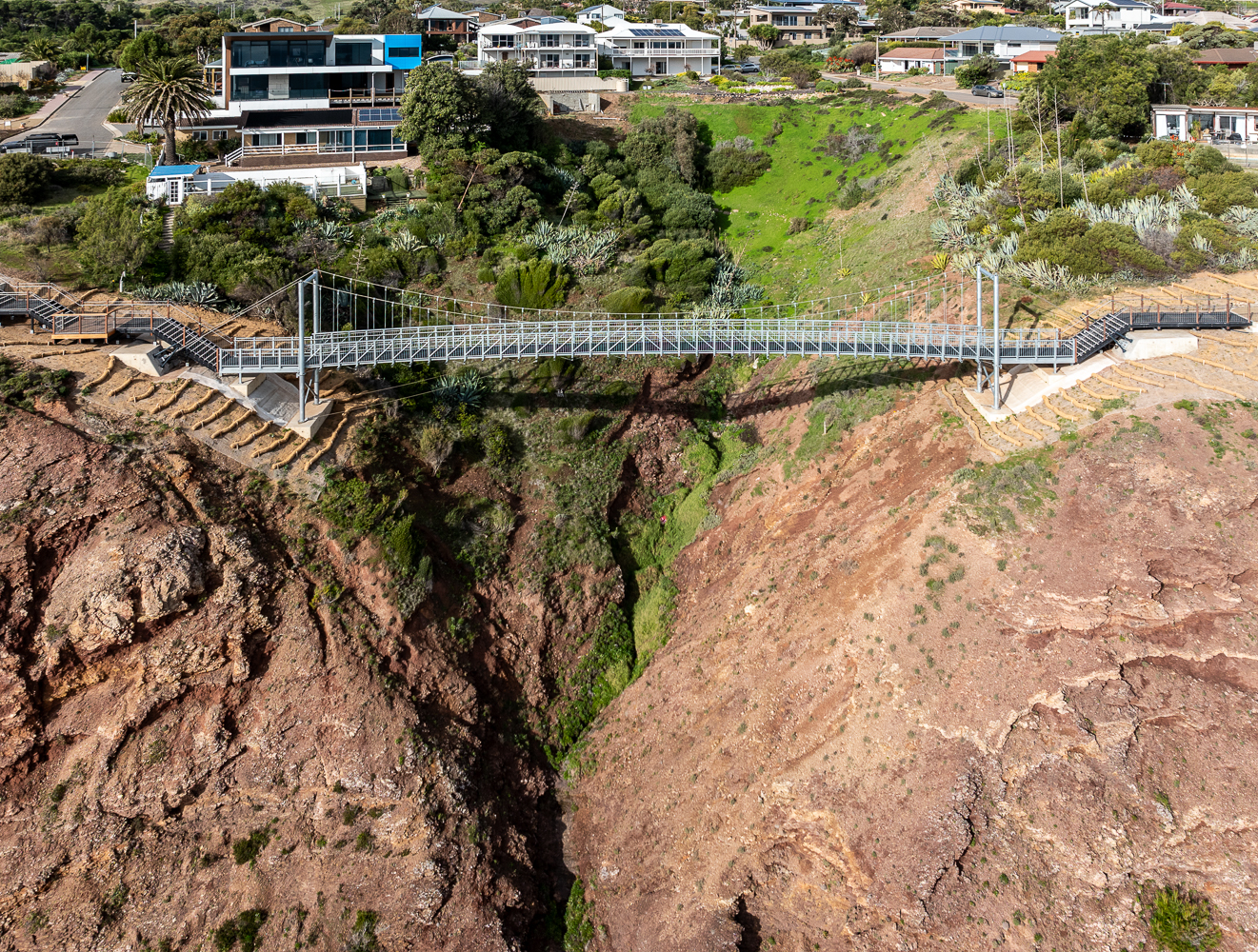 Aerial view of the bridge over cliff tops, with houses in the background